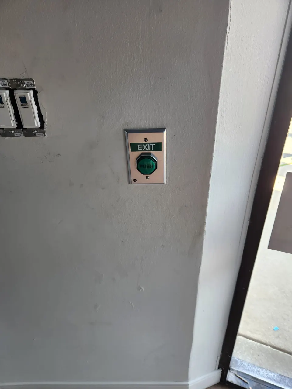 Commercial access control push-to-exit button mounted beside doorway