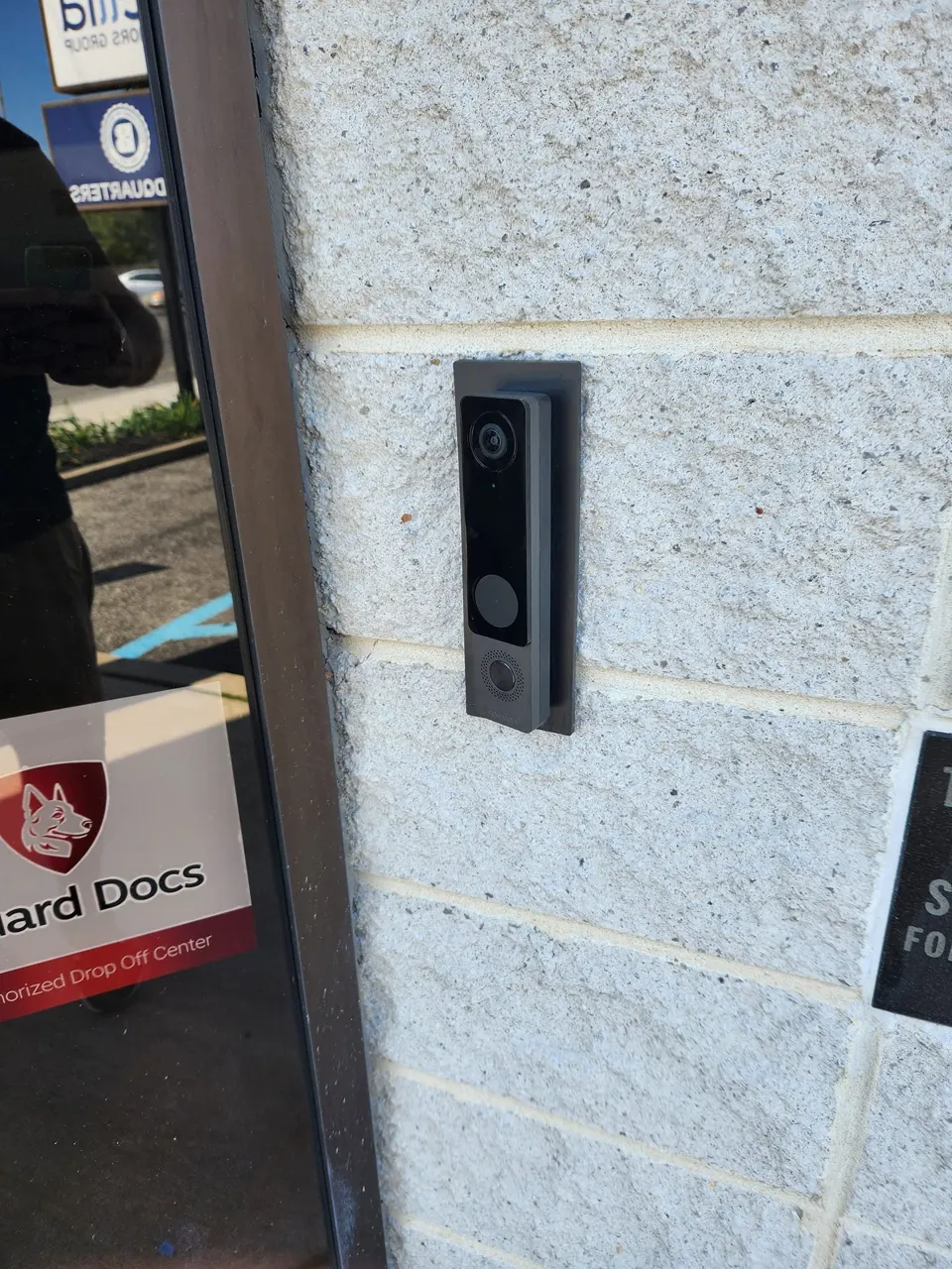 Exterior commercial video door-entry device mounted beside glass entrance