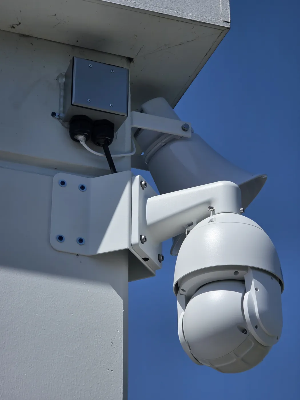Close-up of an exterior pan tilt zoom security camera mounted on a commercial building