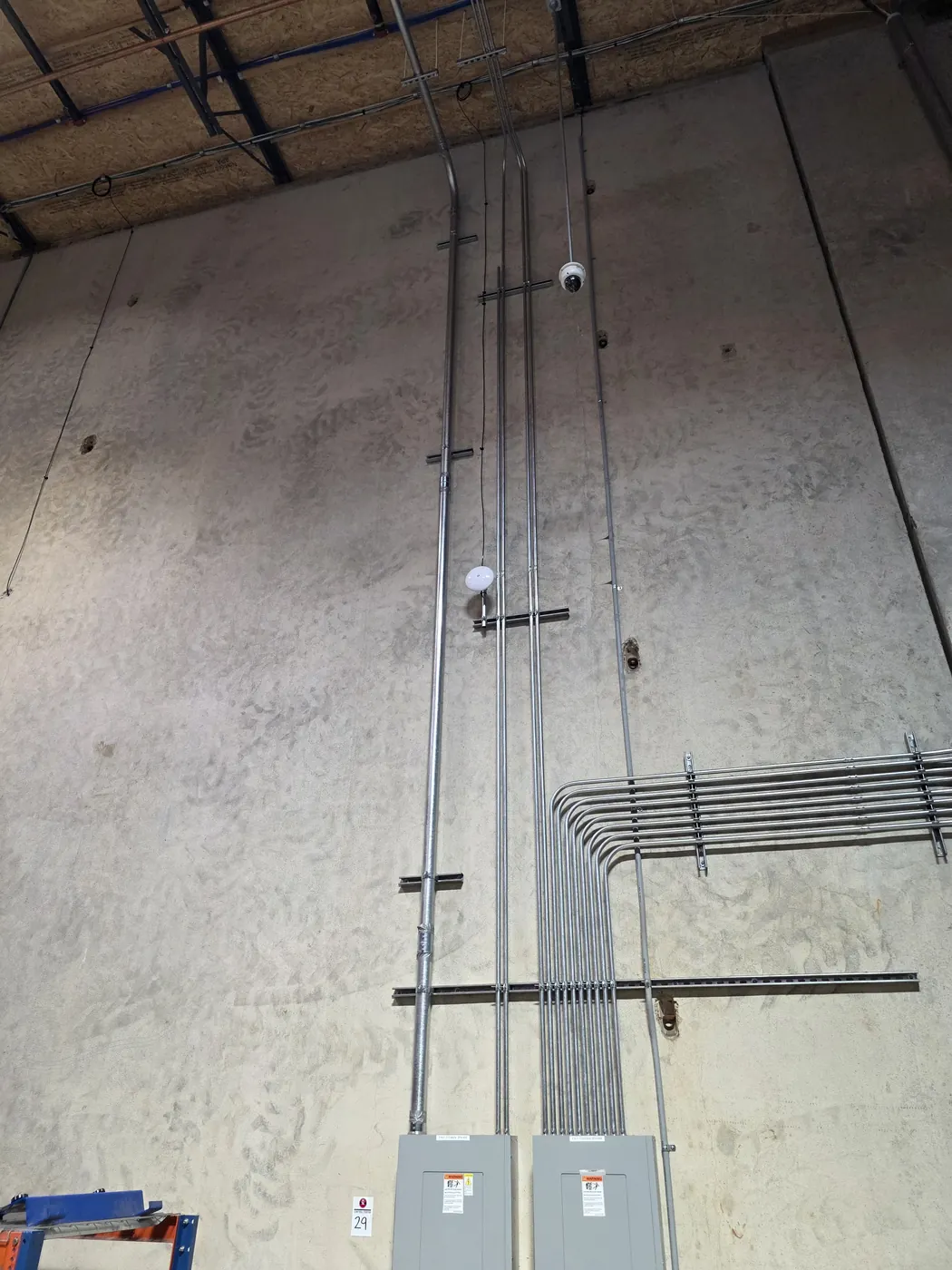 Commercial security camera conduit and cabling installed along an industrial wall